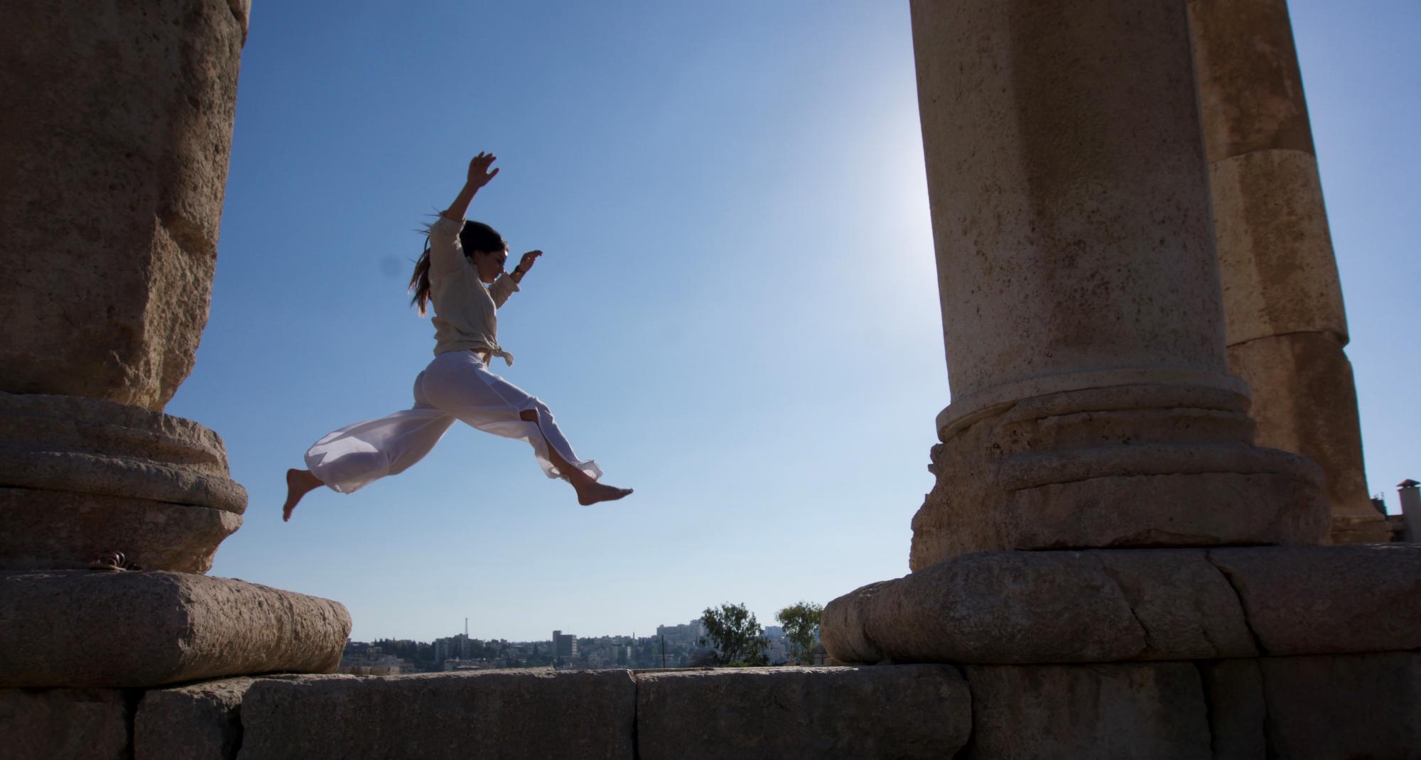 A person jumping through ruins in the Middle East.